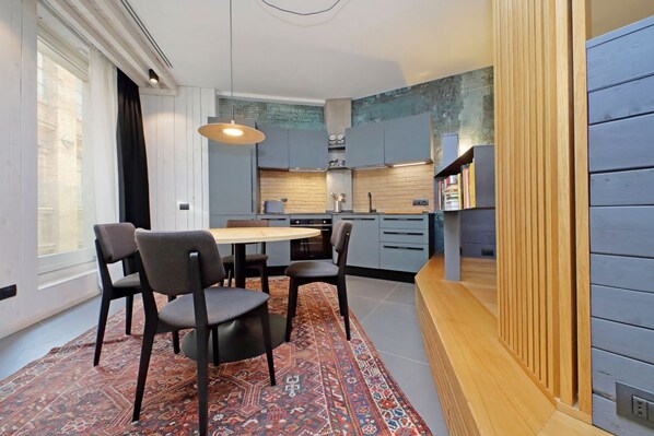A modern kitchen with grey cabinets, a wooden countertop, and a dining area with a table and chairs.