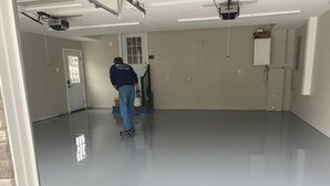 Una habitación amplia y vacía con suelo pulido, una puerta y un ventanal.