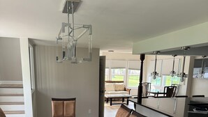 Un comedor con una gran mesa de madera, sillas acolchadas y una lámpara moderna.