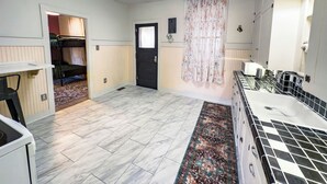 A compact hotel room with a bed, a small kitchenette, a bathroom with a shower, and a large window.
