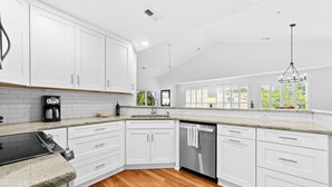 Une cuisine moderne avec des meubles blancs, une cuisinière encastrée et un lave-vaisselle.