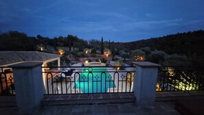 A rooftop pool with a view of a landscaped garden and distant hills.
