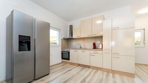 Una cocina moderna con electrodomésticos de acero inoxidable, suelo de madera clara y armarios de tonos neutros.