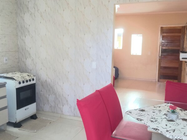 A kitchen with a white stove, a red chair, and a table with a floral tablecloth.