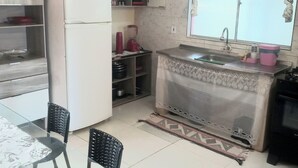 Uma cozinha compacta com geladeira, pia e área de refeições com cadeiras.