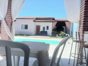 A patio area with a pool, a table, and chairs. - Sophia's beach house (Estância)