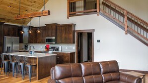 Una cocina amplia con armarios de madera, una isla grande con taburetes de bar y un sofá de cuero.