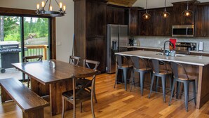 Una cocina moderna con armarios de madera oscura, electrodomésticos de acero inoxidable y una isla central con taburetes de bar.