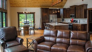 Un salón espacioso con muebles de cuero, techo de madera y vistas al exterior.