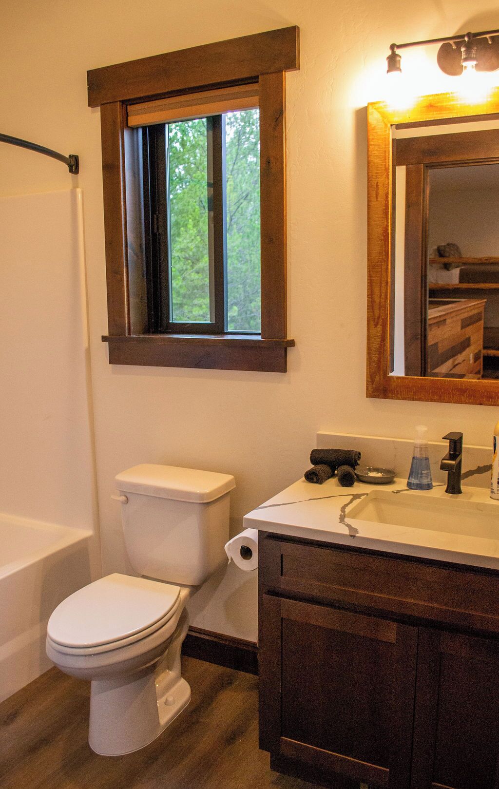 A bathroom with a toilet, a bathtub, a sink, and a window with a view of trees.