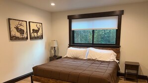 Une chambre à coucher avec un lit en bois, une table de chevet avec une lampe et deux tableaux représentant des cerfs accrochés au mur.