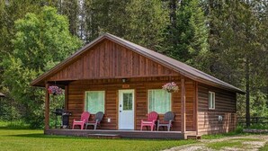 A wooden cabin with a porch, two windows, and a door.