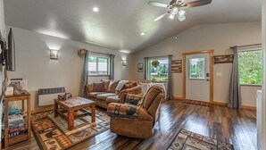 A spacious living room with a ceiling fan, wooden flooring, and a large sofa.