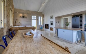 A spacious kitchen with a long wooden table, blue chairs, a built-in island, and a large refrigerator. - Lovely home in Port-des-Barques (Port-des-Barques)
