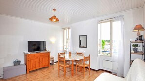 A room with a TV, wooden cabinet, dining table, chairs, and a window with a view. - Gorgeous apartment in Port-Vendres with WiFi (Port-Vendres)