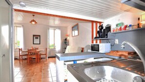 A kitchen with a sink, microwave, and wooden cabinets. There is a dining area with chairs and a table. - Gorgeous apartment in Port-Vendres with WiFi (Port-Vendres)