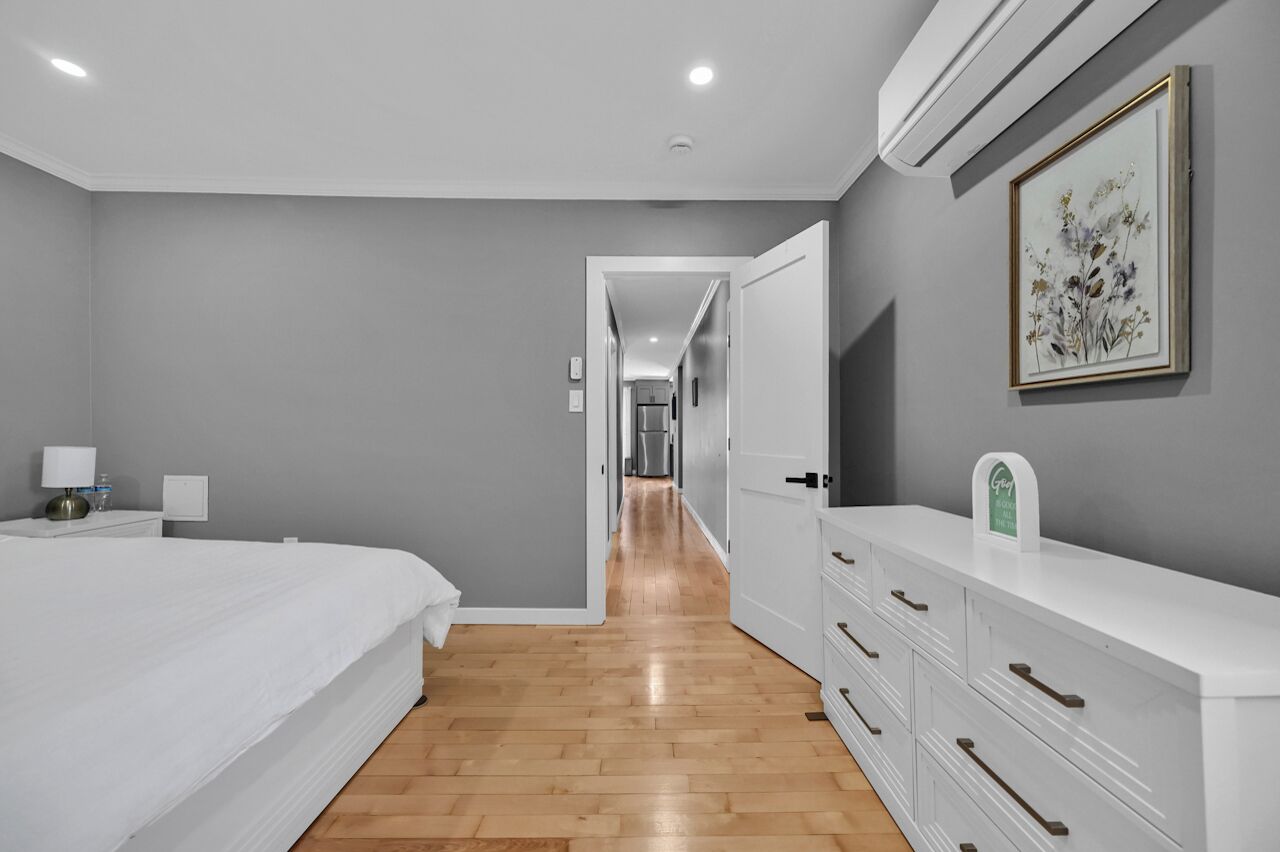 Une chambre à coucher moderne avec un grand lit, une commode et une œuvre d’art encadrée accrochée au mur.
