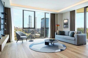 A modern living room with a city view, a sofa, a chair, a coffee table, and a TV.