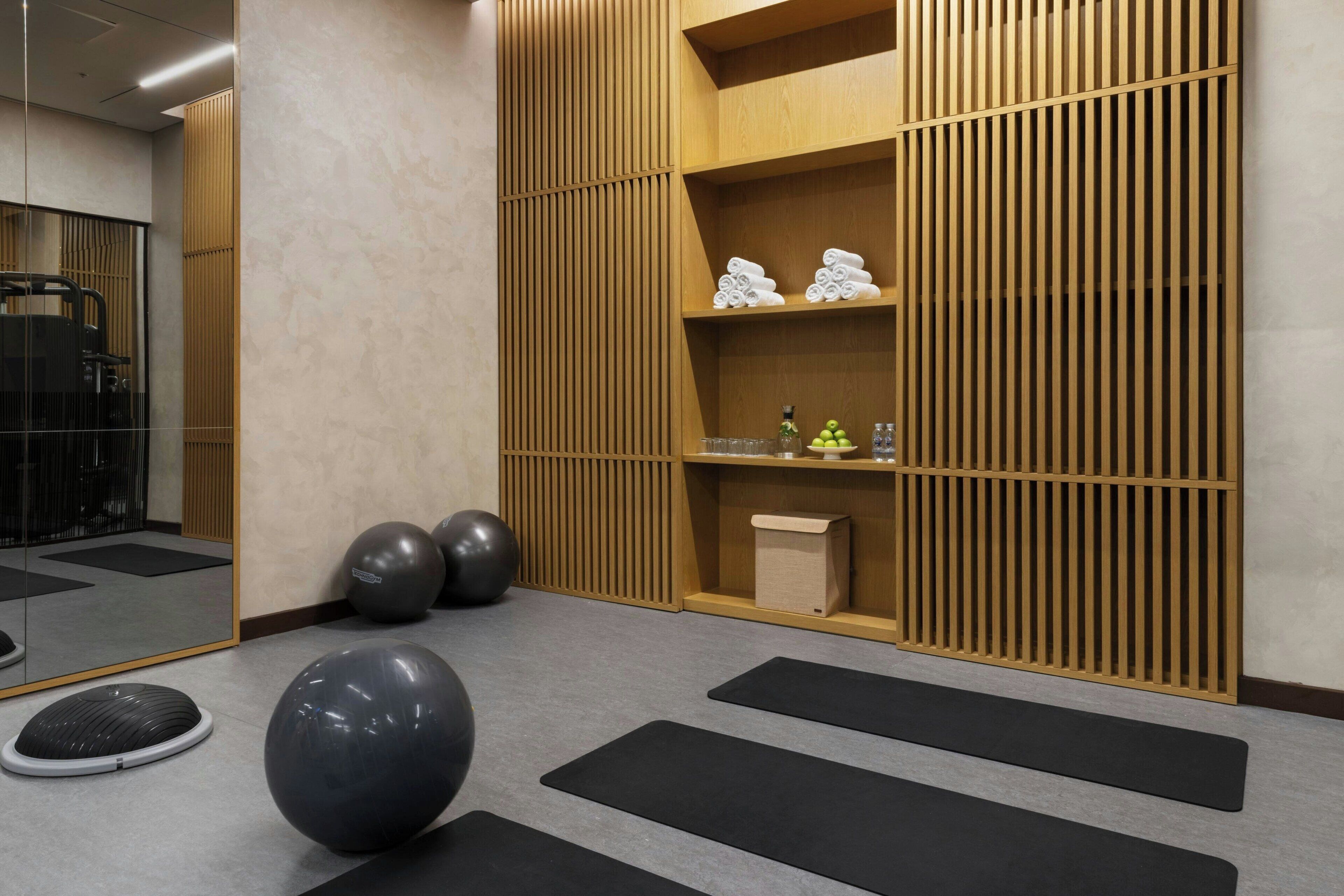 Ein Raum mit Trainingsbällen, Matten und einem Holzregal mit Handtüchern und Flaschen.