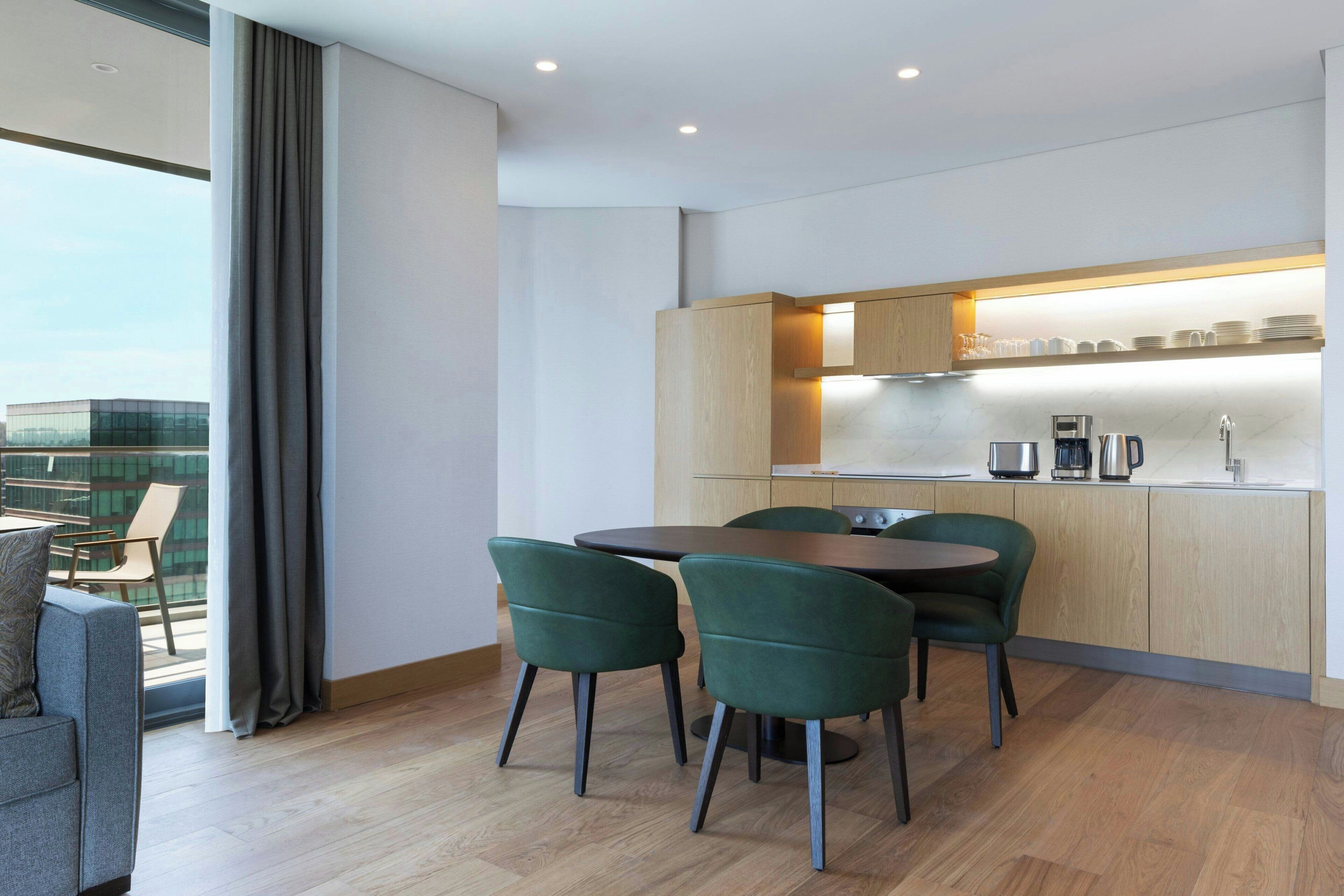 A modern kitchen with a dining area, wooden cabinets, and a view of the city.