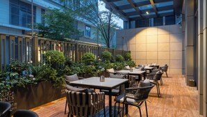 An outdoor dining area with tables and chairs, surrounded by greenery and a wooden floor. - Four Points By Sheraton Shanghai International Tourism And Resorts Zone (Shanghai)