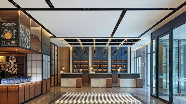 A modern hotel lobby with a checkered floor, a reception desk, and a bar area with shelves of bottles. - Four Points By Sheraton Shanghai International Tourism And Resorts Zone (Shanghai)