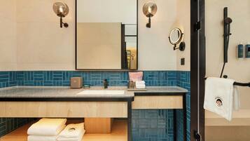 Un baño moderno con tocador de madera, un espejo grande, luces empotradas y un perchero para toallas.