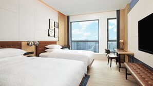 A hotel room with two beds, a desk, a chair, a bench, and a large TV. - Four Points By Sheraton Shanghai International Tourism And Resorts Zone (Shanghai)