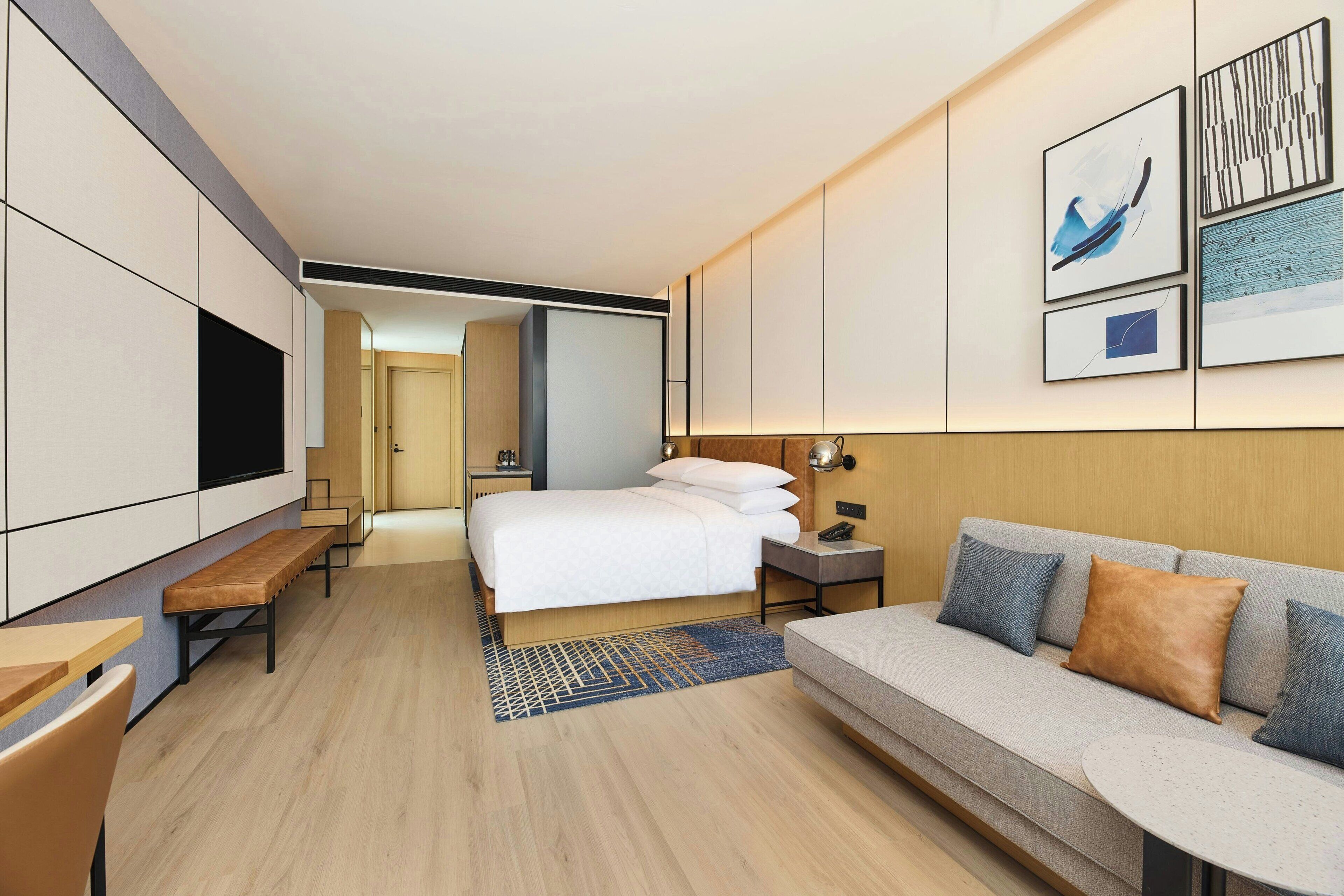 Een moderne hotelkamer met een bed, een bank, een bureau en een televisie.
