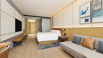 Een moderne hotelkamer met een bed, een bank, een bureau en een televisie.