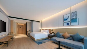 Una habitación de hotel moderna con una cama grande, un sofá, una mesita y un televisor.