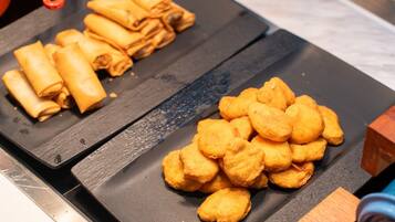 A kitchen counter with two trays of food items, one with rolled items and the other with fried items.
