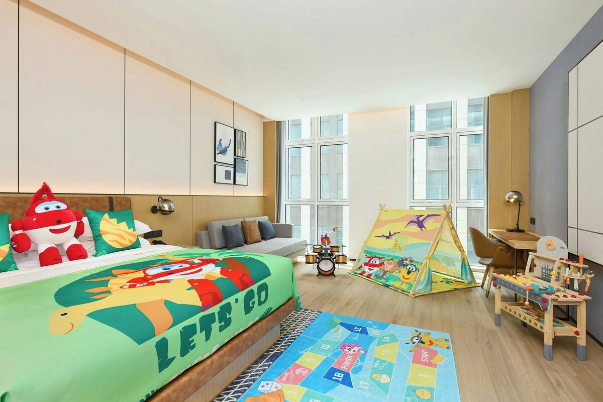 A child's bedroom with a bed, a play area, and a window.