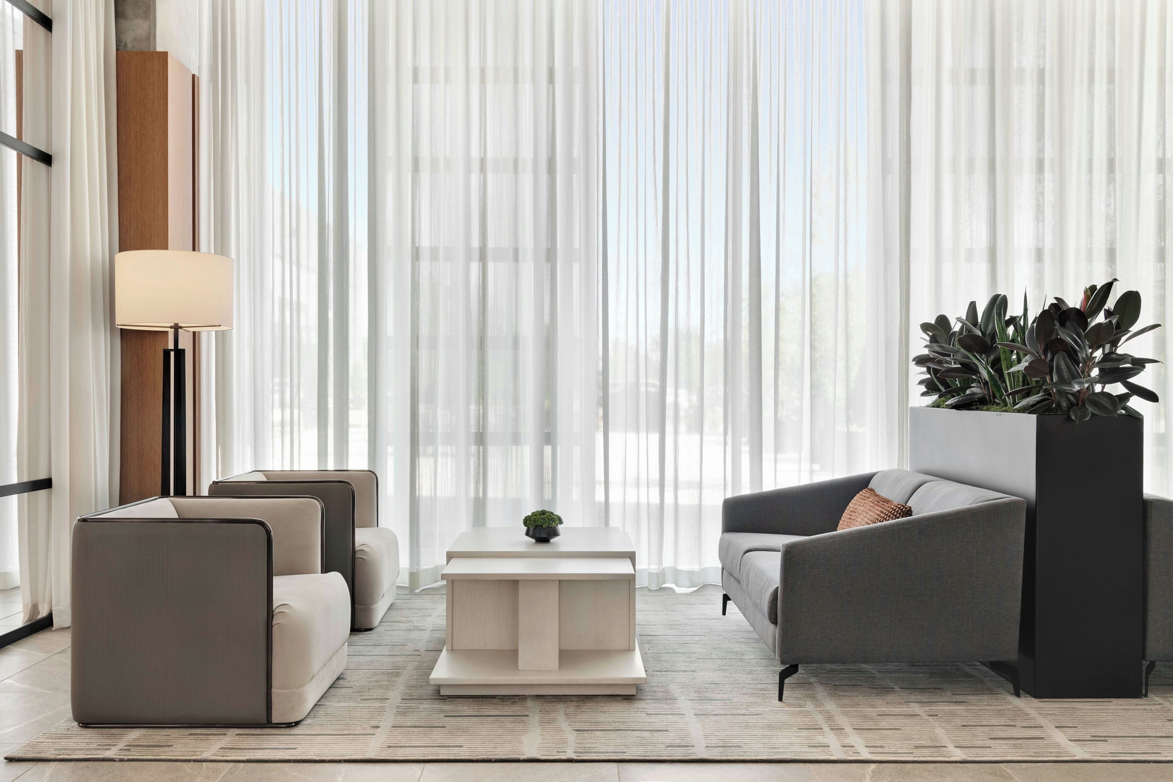 A modern living room with a sofa, armchairs, a coffee table, and a floor lamp.