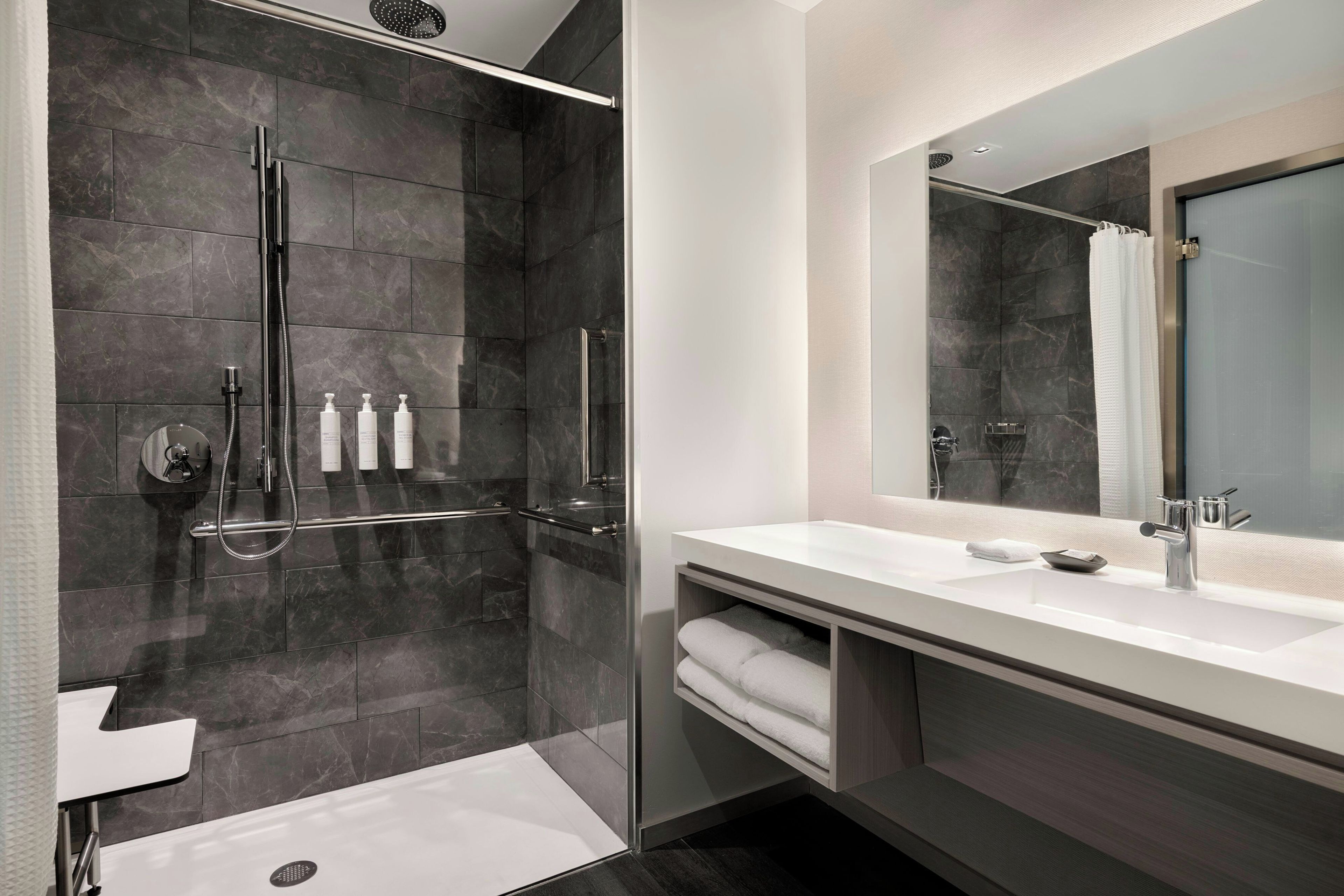 A modern bathroom with a glass-enclosed shower, a white sink, and a large mirror.