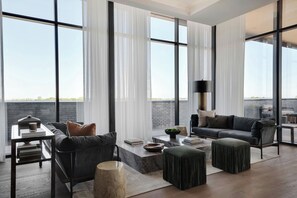 A modern living room with a sofa, ottoman, coffee table, and a side table with books and a lamp. - Ac Hotel Bentonville (Bentonville)