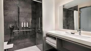 Une salle de bain moderne avec une douche à parois de verre, un lavabo blanc et un grand miroir.