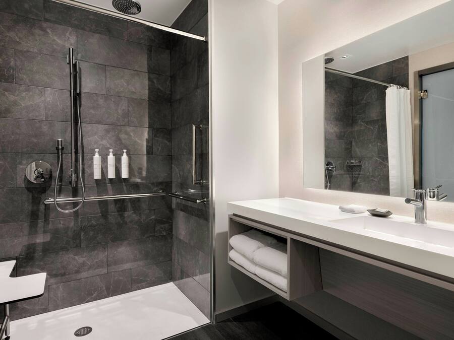 Une salle de bain moderne avec une douche à parois de verre, un lavabo blanc et un grand miroir.