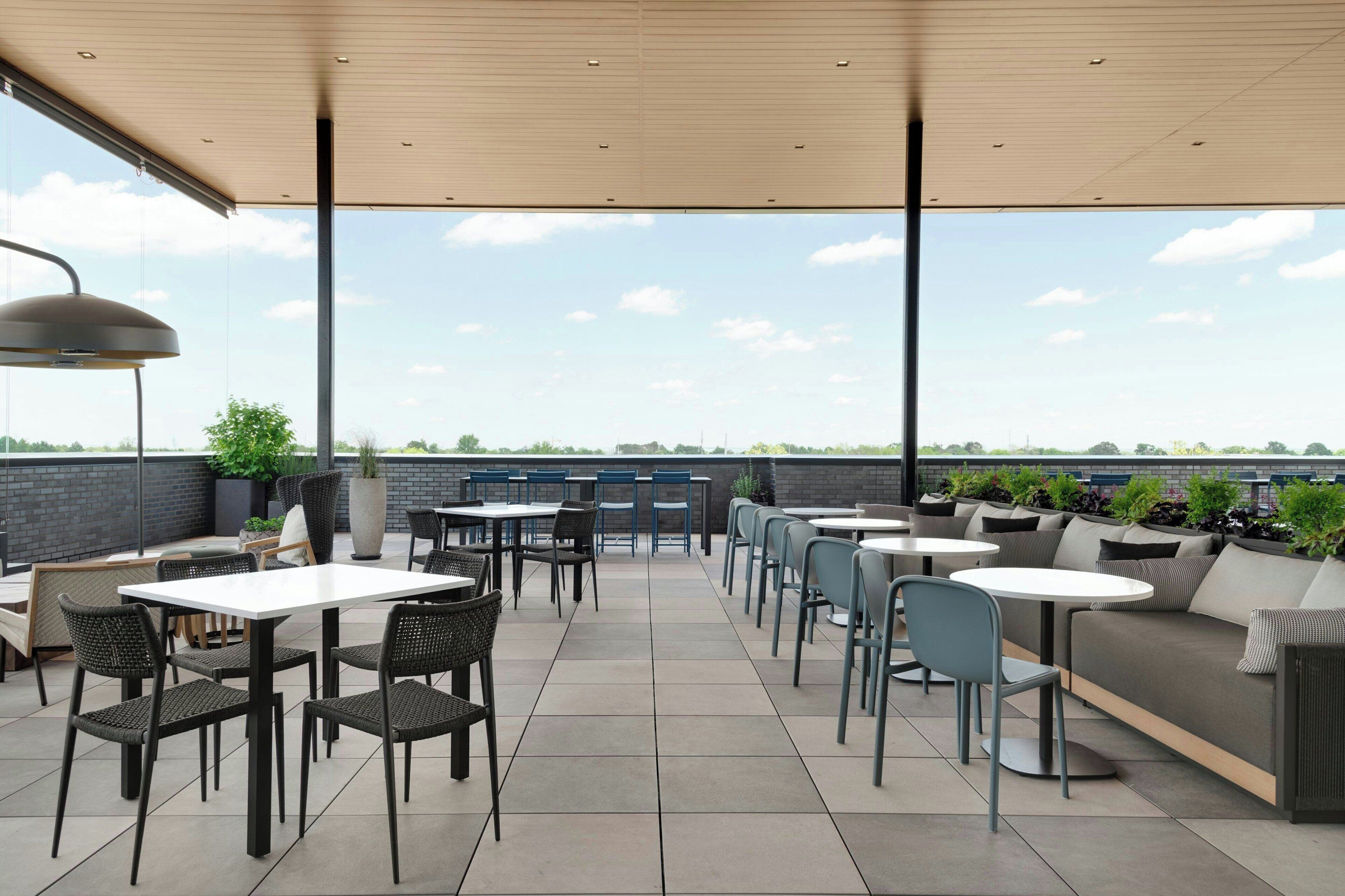 An outdoor patio area with tables and chairs, a sofa, and potted plants.