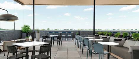An outdoor patio area with tables and chairs, a sofa, and potted plants.