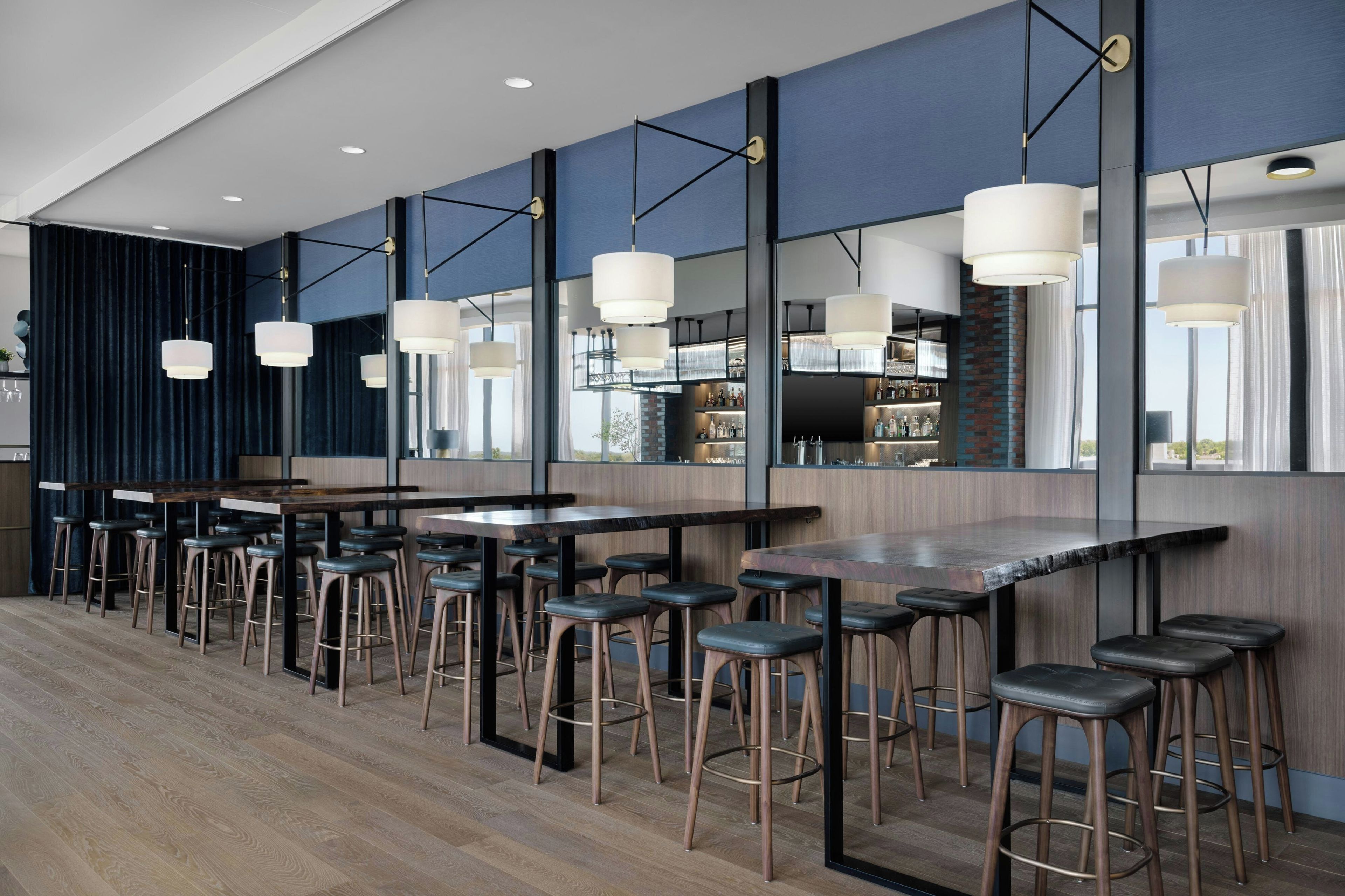 A modern bar area with multiple stools, a long counter, and pendant lighting.