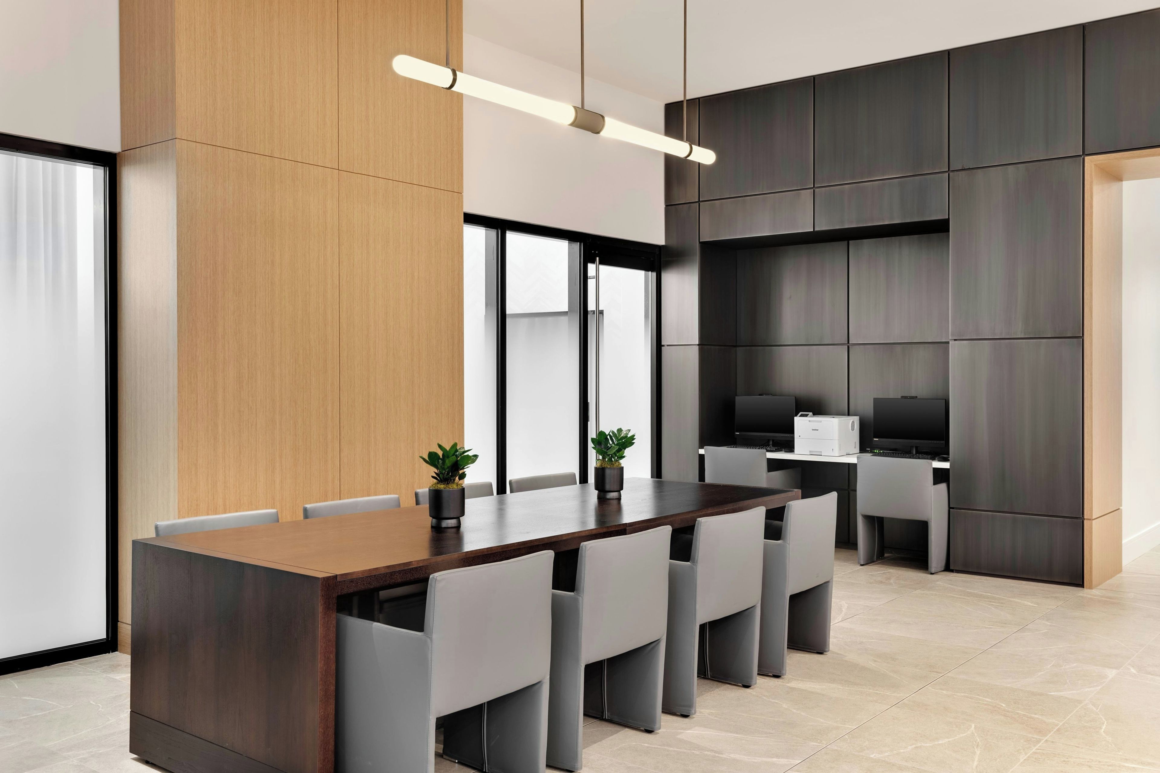 A modern conference room with a long table, chairs, a television, and a printer.