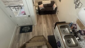 A kitchen with a wooden floor, a dark brown sofa, and a white door with a window. - Cozy fisherman cabin step from Lake Sam Rayburn (Etoile)