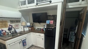 A compact kitchen with a built-in microwave, a refrigerator, and a small dining area. - Cozy fisherman cabin step from Lake Sam Rayburn (Etoile)