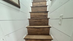Un escalier étroit avec des marches en bois et des murs blancs.