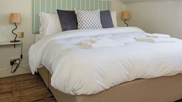 Een slaapkamer met een bed, bedlampen, een stopcontact en een houten vloer.