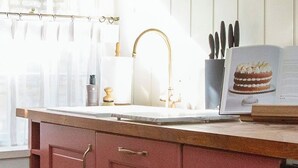 Een keuken met een marmeren aanrecht, een spoelbak en een raam met gordijnen.