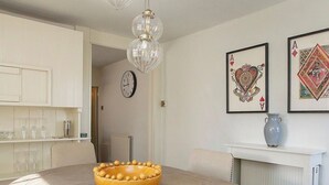 Een eetgedeelte met een ronde tafel, een gele kom en een kroonluchter.