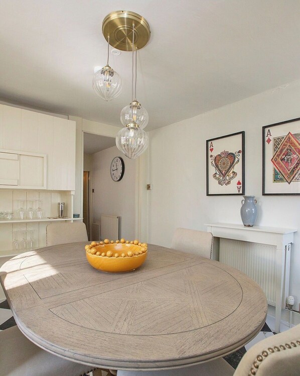 A dining area with a round table, a yellow bowl, and a chandelier.