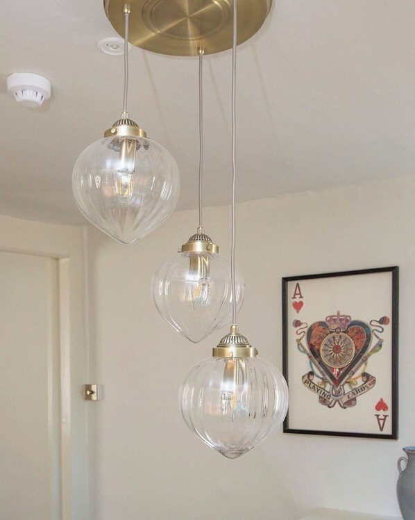 A room with three hanging crystal pendant lights, a framed playing cards artwork on the wall, and a white door. - Spacious 3 bedroom home over 2 floors (Cirencester)